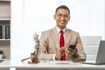 Middle-aged Asian indian people male lawyer meticulously reviews legal documents. Courtroom judge hammer and goddess scales. Depicting the essence of legal counseling and comprehensive services.