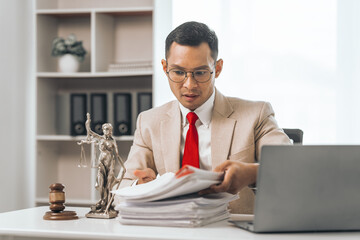 Middle-aged Asian indian people male lawyer meticulously reviews legal documents. Courtroom judge...