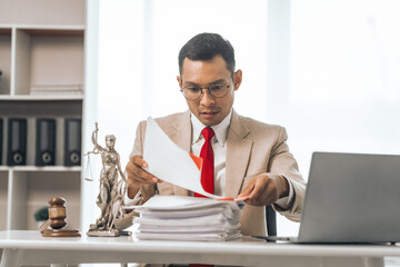 Middle-aged Asian indian people male lawyer meticulously reviews legal documents. Courtroom judge...