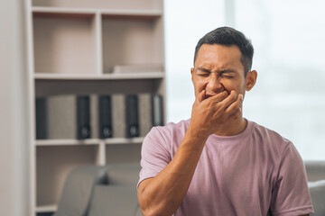 Middle-aged Asian Indian man with gum disease, toothache, wisdom tooth and molar pain. sitting on...