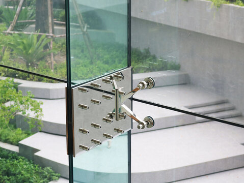 Stainless steel splice plate spider fittings installed on glass rib structure wall.