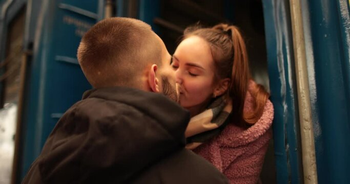 A young couple in love hug and say goodbye before the girl gets on the train to leave. Farewell at the station.