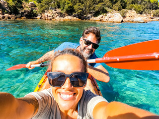 Happy active adult couple enjoying kayak canoe excursion trip tour on transparent blue clean water at the sea. Concept of happiness man and woman in summer holiday vacation. Healthy lifestyle. Tourist