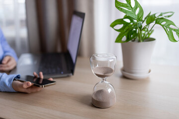 Hourglass on the table for business deadline. Time concept - obrazy, fototapety, plakaty
