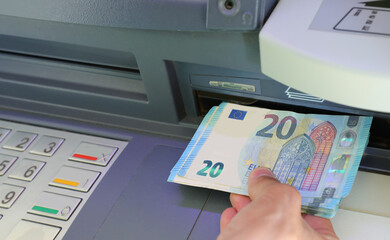 Hand of person withdrawing twenty euros banknotes in a bank ATM i