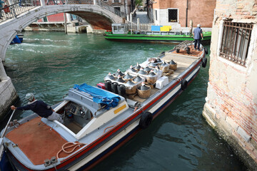 boat for transporting goods on canals of the islands of Venice in Italy with large demijohns of wine