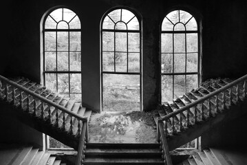 stone staircase with concrete railings and an old big arched window in destroyed castle - interior of abandoned architecture of empire style building. front view. © Maxim Chuev