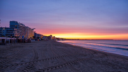 Amazing view of a fiery sunrise with multicolored clouds. Sea waves along the seashore at sunrise. Morning time. Ocean view. La Baule-Escoublac, France