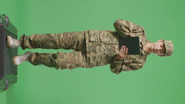 Full Body Of Asian Man Soldier Using A Tablet While Walking In The Green Screen Background Studio
