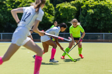 Two female field hockey players fighting for the ball on the pitch