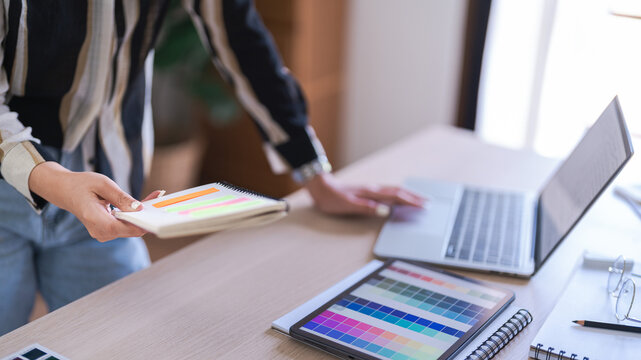 Graphic designer women reading data on laptop and selection color to working about graphic design