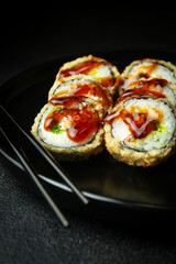 Sushi rolls in a dark plate on a black background