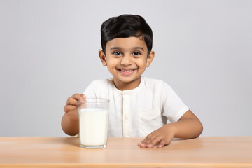 Cute Indian little boy drinking milk in glass.