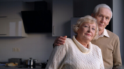 Portrait of a nice senior couple hugging and looking at the camera, secure retirement, happiness