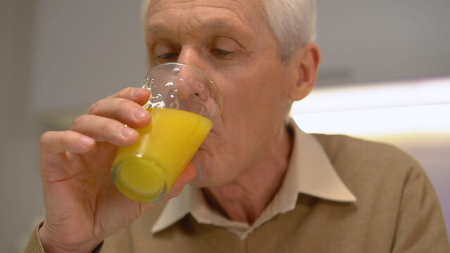 An old man drinking fresh orange juice for healthy, vitaminized nutrition in an active life - Powered by Adobe