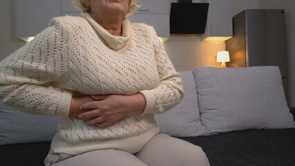 A senior woman suffering from gallbladder discomfort, liver inflammation or infection, requiring medical attention