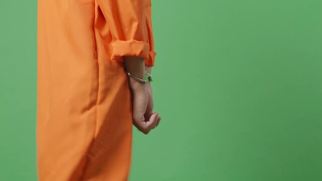 Side View Close Up Of Male Prisoner'S Hands In Handcuffs While Walking On The Green Screen Background

