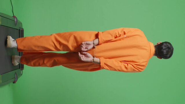 Back View Full Body Of Asian Male Prisoner In Handcuffs Walking On The Green Screen Background
