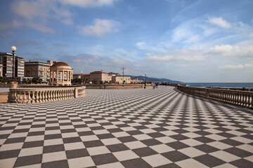 Fototapeta na wymiar Leghorn (Livorno), Tuscany, Italy: landscape of the promenade Mascagni Terrace, a picturesque seashore on the Ligurian sea with black and white checkered pavement and columned bannister