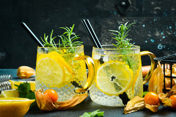 Gin and tonic cocktail with lemon and rosemary with ice. On a dark stone table. Drinks