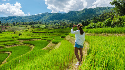 Fototapeta na wymiar Asian woman watching the Terraced Rice Field in Chiangmai during the green rain season, Thailand. Royal Project Khun Pae Northern Thailand