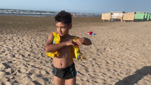 a 9-year-old boy on the seashore puts on a life jacket