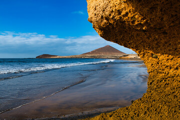 Tranquil Dawn: El Médano's Golden Hour with Waves, Rocks, and Sand