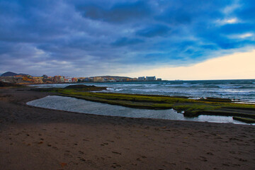 Tranquil Dawn: El Médano's Golden Hour with Waves, Rocks, and Sand