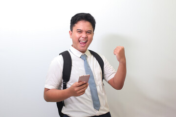 Indonesian senior high school student wearing white shirt uniform with gray tie raising his fist,...