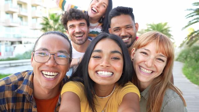 Multiracial friends taking selfie video with smart mobile phone outside - Happy young people having fun talking on city street - Life style concept with guys and girls hanging out on a sunny day