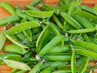 Heap of empty open green pea pods on wooden background