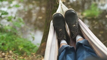 A man is resting in a hammock in a country house. A young guy lies in a hammock, dozing outdoors in the summer in the green of trees in the country