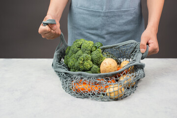 Mesh bag with vegetables, shopping grocery, healthy food ingredients, potato, broccoli and carrots,...