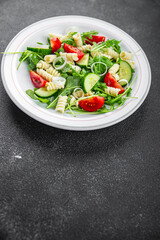 pasta salad fusilli pasta, cucumber, tomato, green lettuce, onion appetizer meal food snack on the table copy space food background rustic top view keto or paleo diet vegetarian vegan food