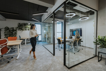 Fototapeta premium Young woman with digital tablet walking in the modern office