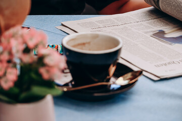 Fototapeta na wymiar A cup of coffee and a newspaper on a table at the restaurant, out of focus on purpose