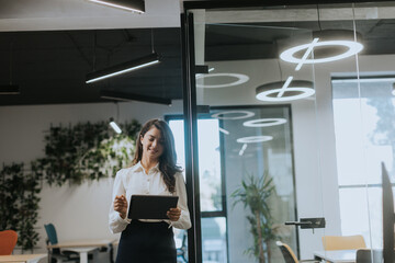 Young woman with digital tablet standing in the modern office