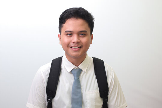 Indonesian senior high school student wearing white shirt uniform with gray tie smiling and looking at camera. Isolated image on white background