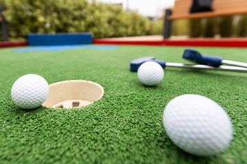 Fun vacation entertainment for summertime. Playing mini golf on green grass outdoors. Setting goals and winning lifestyle concept. Competition at golf course: two crossed sticks. Blank space for copy.