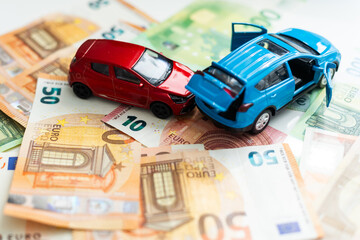 traffic accident of two toy cars and a police car helping in a european banknote background  - Powered by Adobe