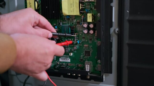 Repairman using multimeter to check motherboard to find the damaged point.