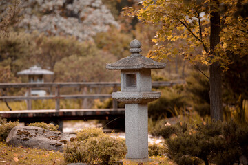 Traditional Japanese stone lantern in the autumn garden. Yellow autumn foliage