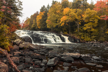 Buttermilk Falls in Long Lake, NY, Adirondacks, surrounded by vivid fall foliage on an overcast afternoon