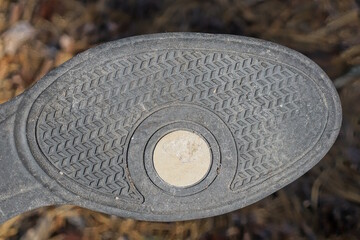 one boot with a rubber dirty old sole with a black white pattern on a brown background