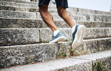 Man, legs and running on stairs in fitness for workout, training or outdoor cardio exercise. Closeup of male person, shoes or feet on steps for sports, health or wellness in an urban town or city