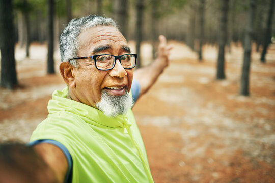 Selfie, excited and senior man hiking for health, wellness or cardio training on a mountain. Smile, nature and happy elderly male person taking a picture on cellphone for outdoor trekking in woods.
