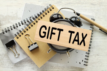 GIFT TAX. table clock gray background .text on wooden block
