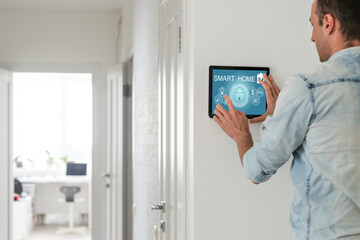 Young electrician installing security alarm on wall