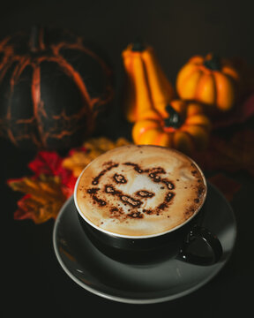 Halloween cappuccino coffee with a scary spooky pumpkin latte art and decorations