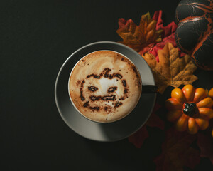 Halloween cappuccino coffee with a scary spooky pumpkin latte art and decorations